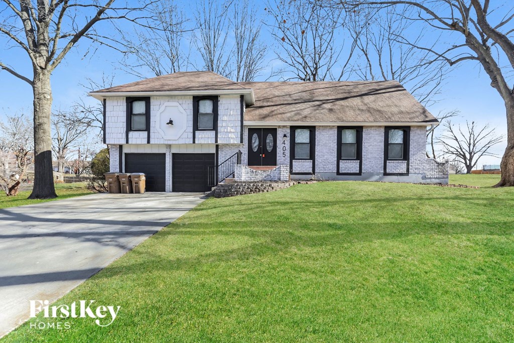 a white house with black shutters and a lawn