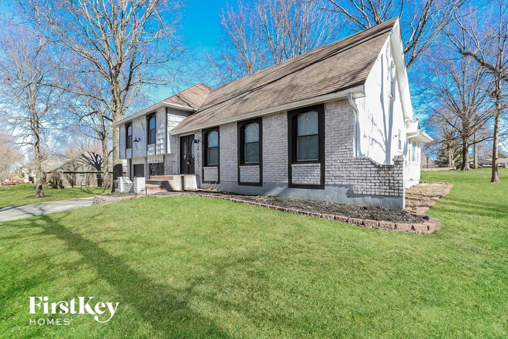 a white brick house with black shutters and a green lawn