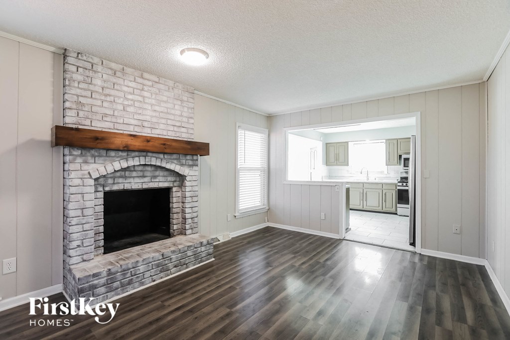 a living room with a brick fireplace and wooden floors