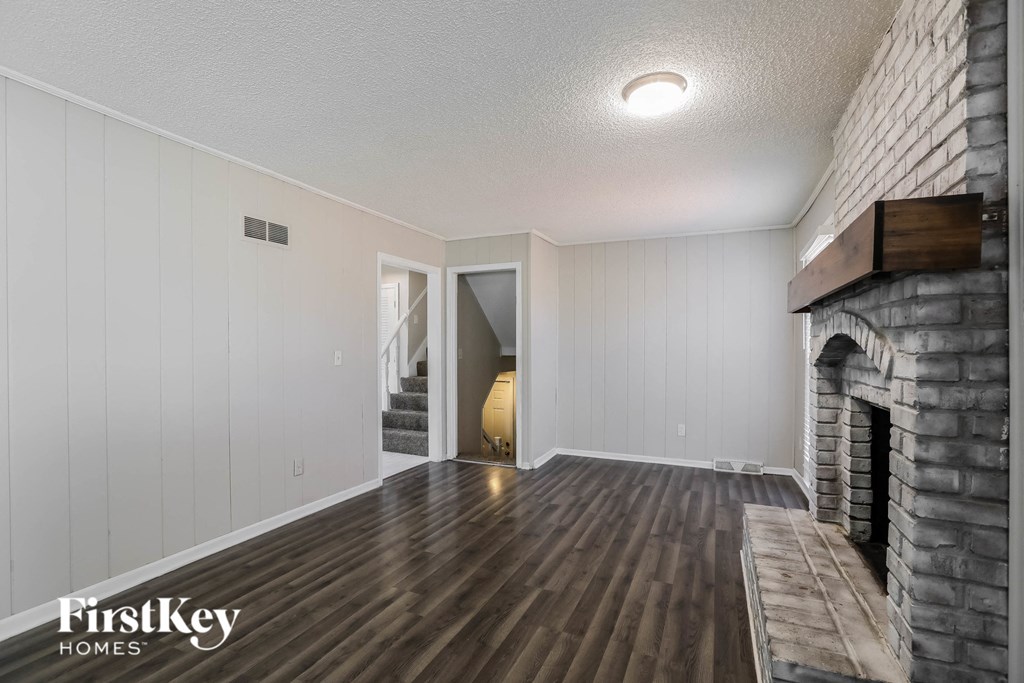 a living room with a brick fireplace and wooden floors