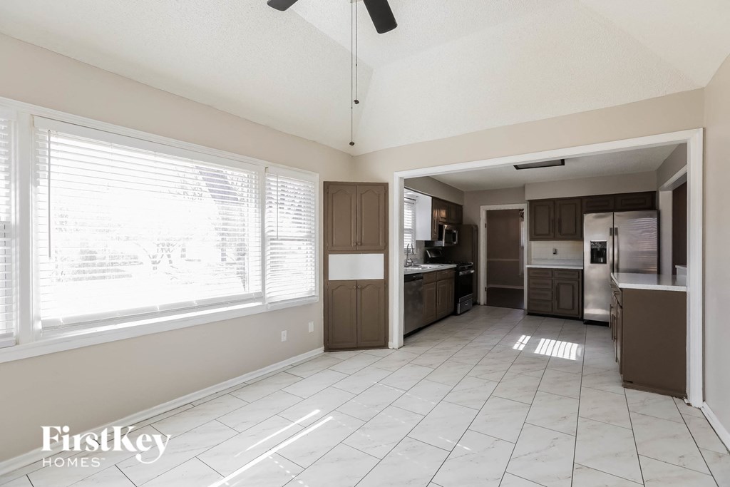 a kitchen with a large window and a white tiled floor