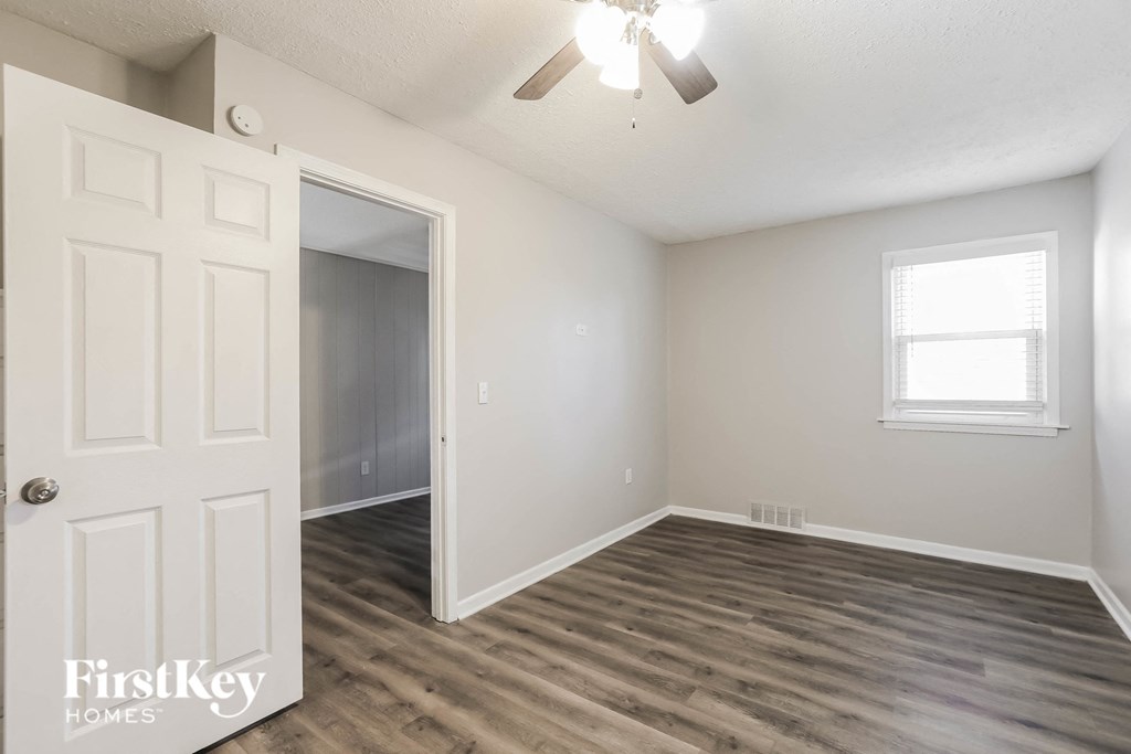 an empty living room with a white door and a ceiling fan