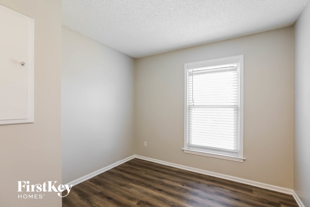 a bedroom with white walls and a window and wooden floors