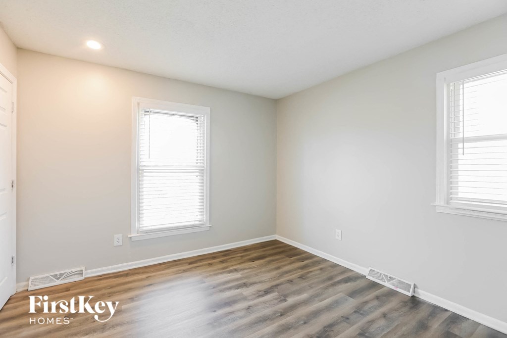 the spacious living room with hardwood flooring and two windows