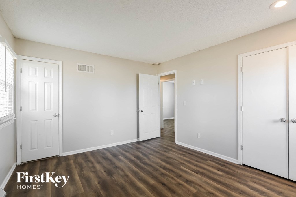 the living room of an apartment with white walls and wood flooring