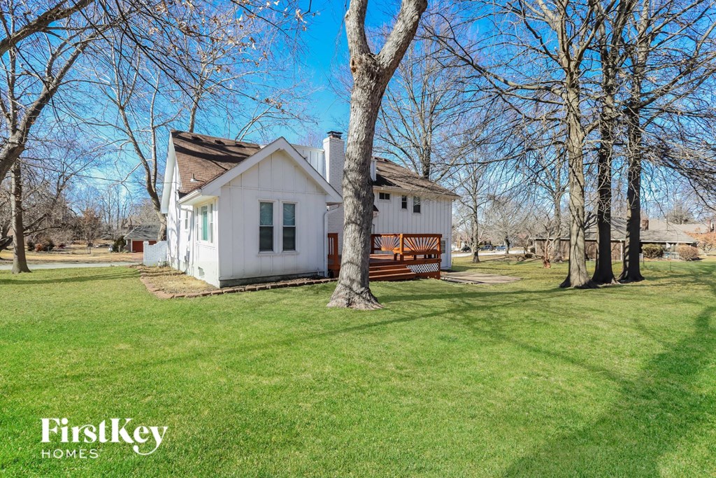 a small white house with a yard and a deck