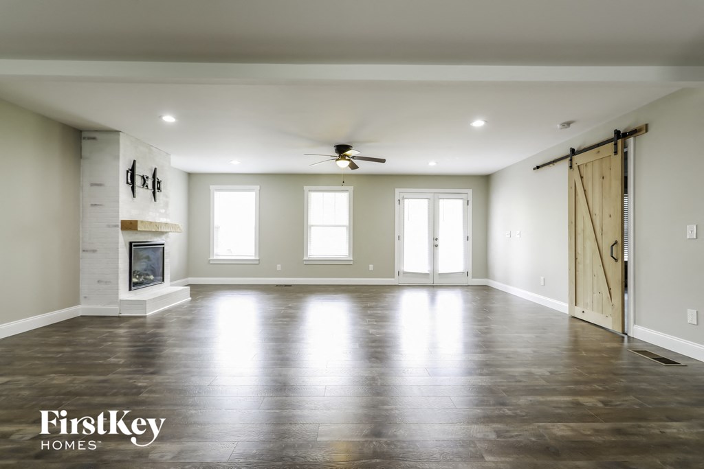 an empty living room with a fireplace and sliding barn doors