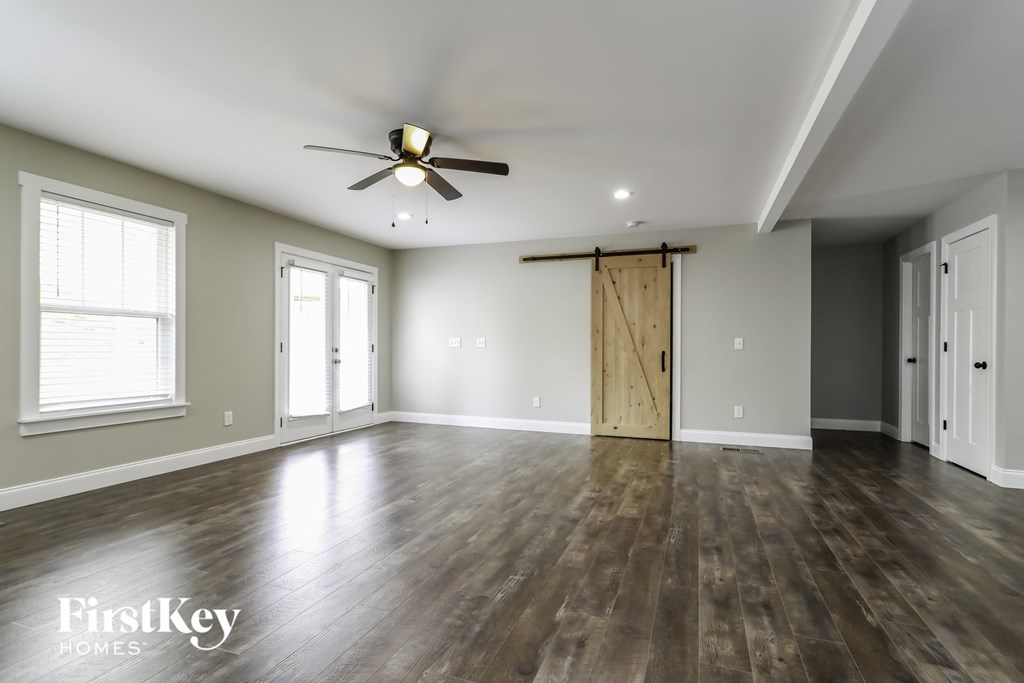 an empty living room with wood floors and a sliding barn door