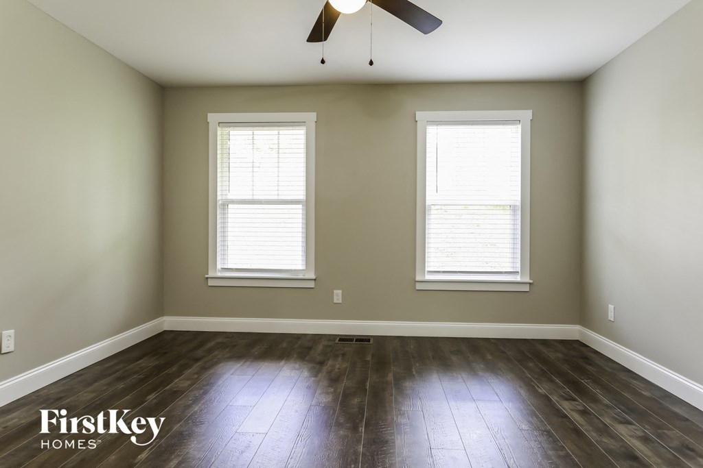 a room with wood floors and two windows and a ceiling fan
