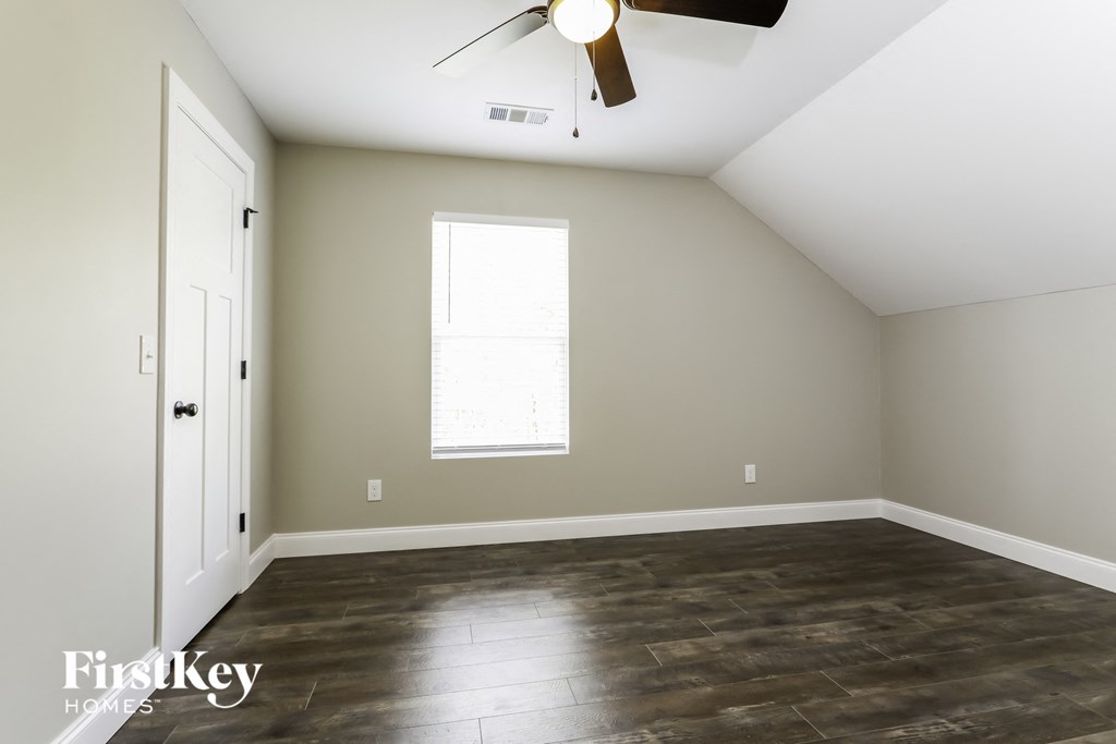 an empty room with wood floors and a ceiling fan