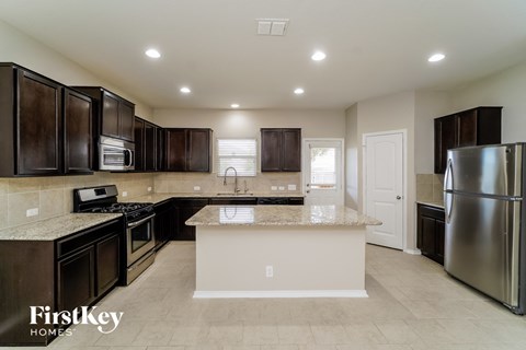 A kitchen with dark brown cabinets and a granite countertop.