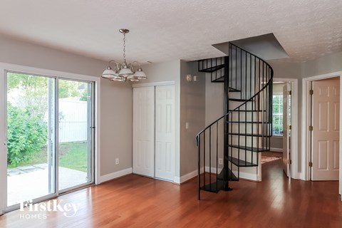 A spacious room with a wooden floor and a black spiral staircase.