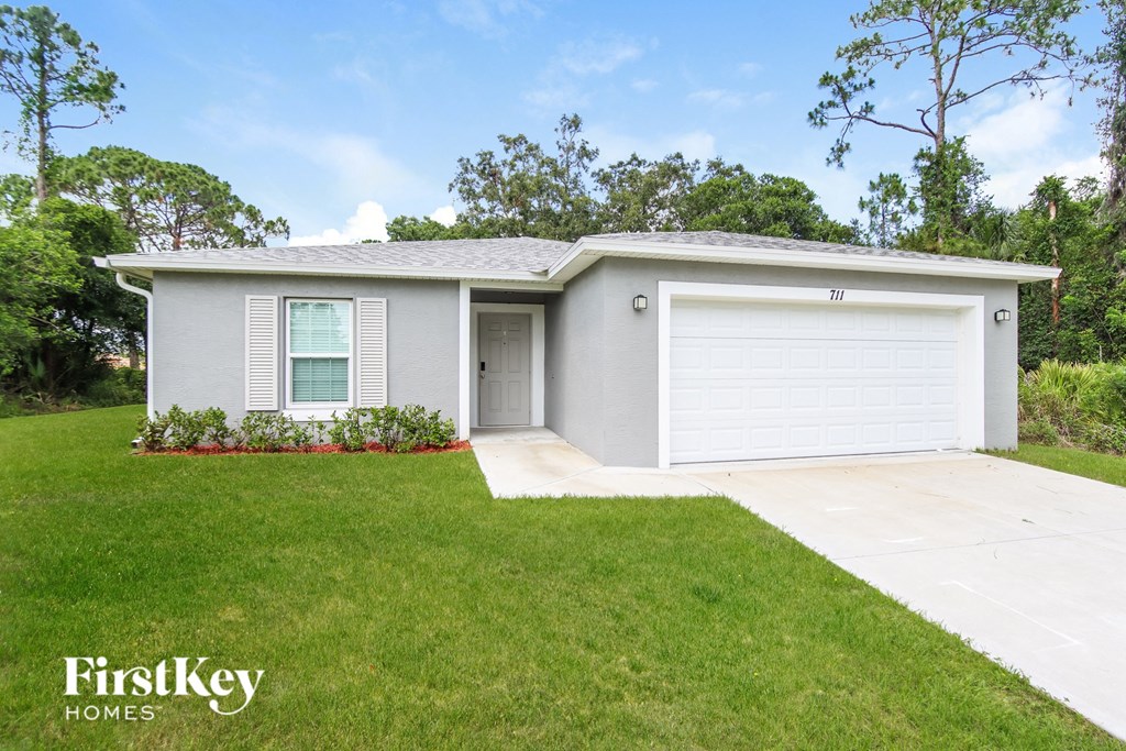 A grey house with a white garage door and a window with white blinds.