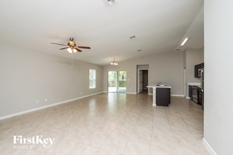 A spacious empty room with a ceiling fan and a door leading to another room.