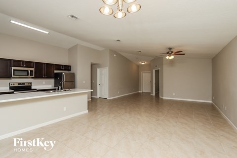 A spacious living room with a kitchen area in the background.