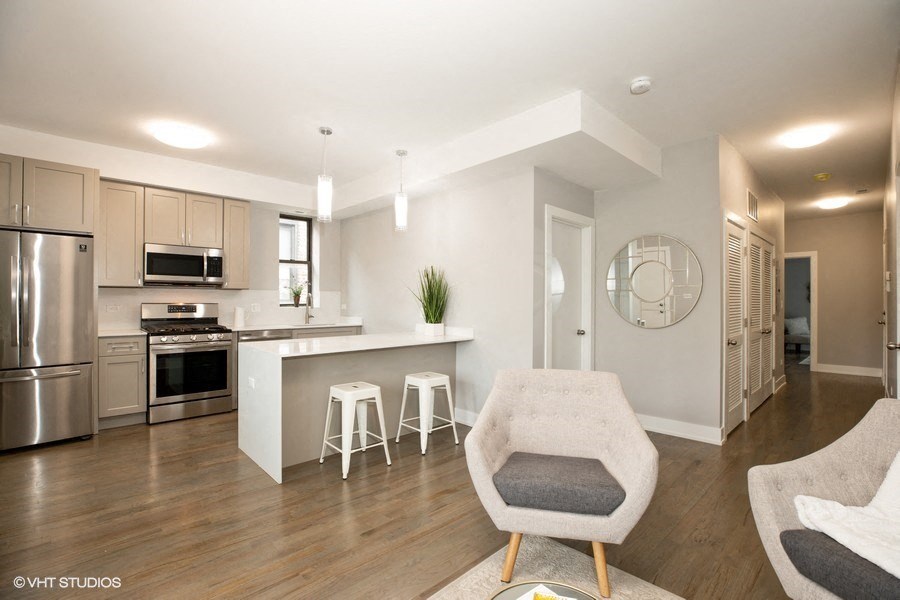 an open kitchen and living room with a bar and stools