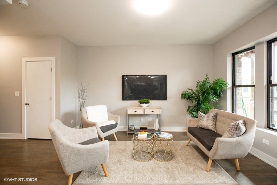 the living room of an apartment with two chairs and a table and a television