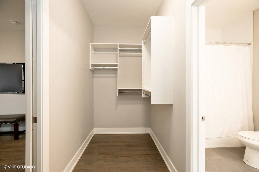 a walk in closet in a bathroom with a toilet and shelves