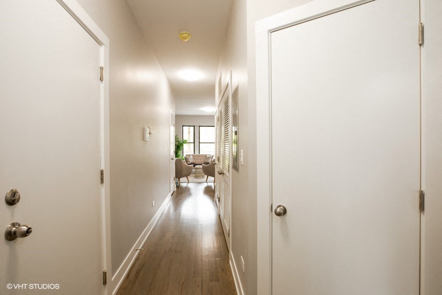 a long hallway with white walls and a door to a living room with a couch