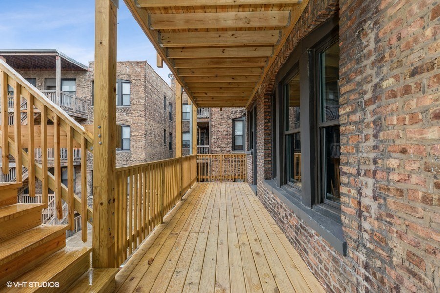 a large porch with wooden floors and a brick wall