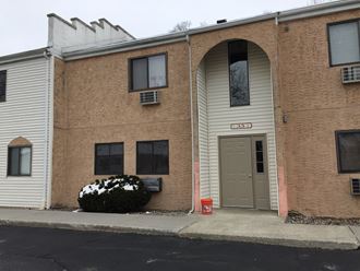 the front of a brick building with a brown door