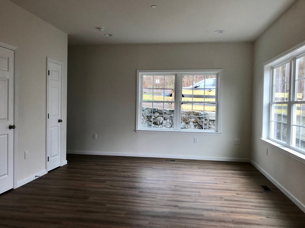 an empty living room with wooden floors and a large window