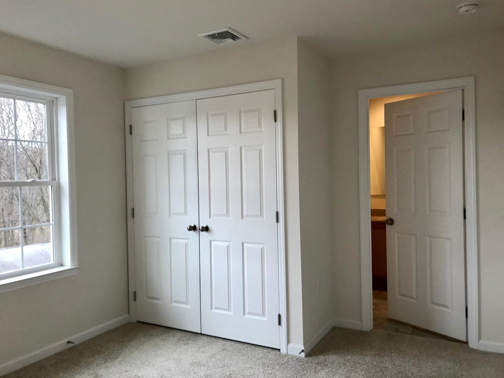 an empty bedroom with two closets and two doors