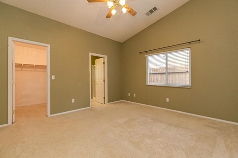 an empty living room with a ceiling fan and a door to a closet
