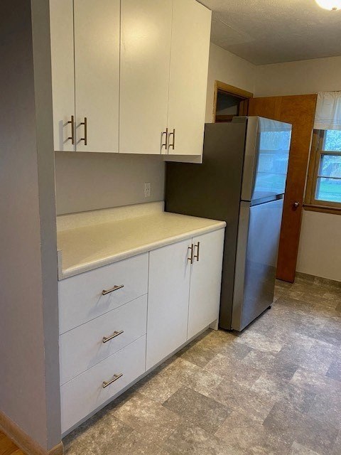 A kitchen with white cabinets and a black fridge.