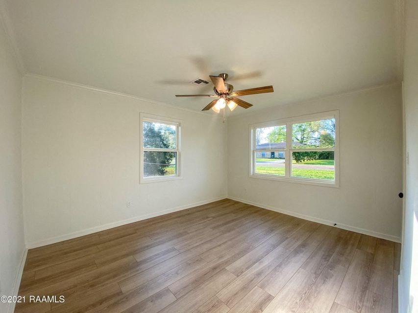 an empty living room with a ceiling fan and a window