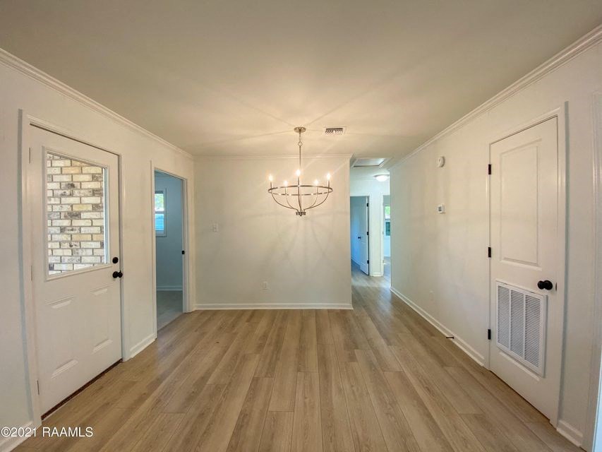 the living room and dining room of a house with white walls and wood floors