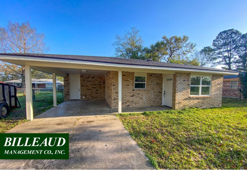 a small brick house with a concrete driveway