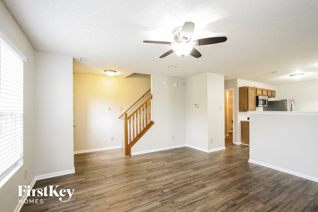 A spacious room with a wooden floor and a ceiling fan.