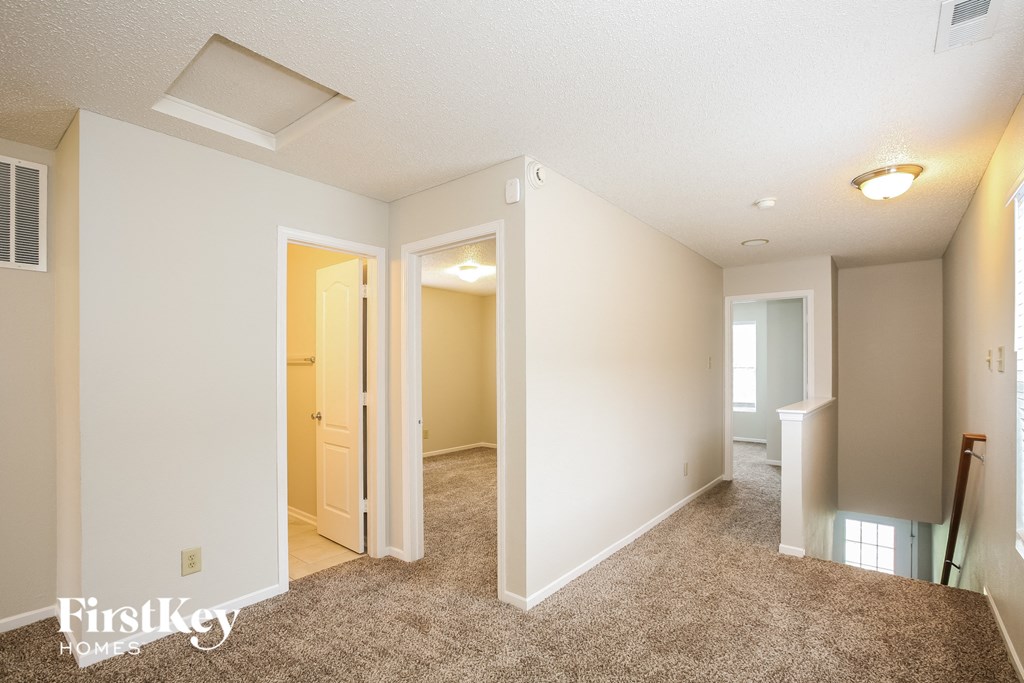 A spacious room with a carpeted floor and a doorway leading to another room.