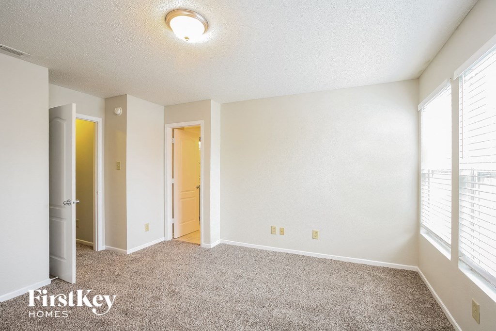 A room with a carpeted floor and a window with blinds.