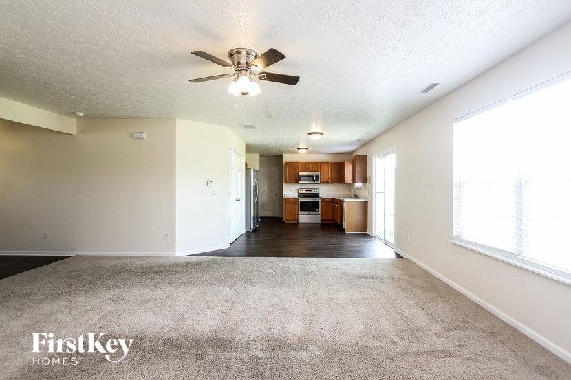 A spacious living room with a carpeted floor and a ceiling fan.