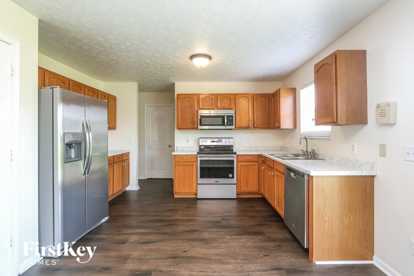 A kitchen with wooden cabinets and a stainless steel refrigerator.