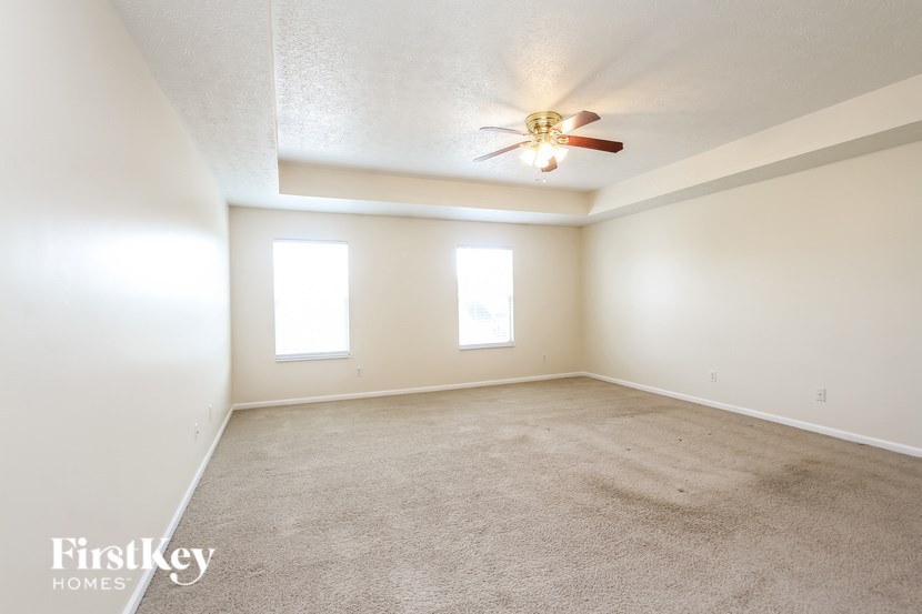 A spacious room with a carpeted floor and a ceiling fan.