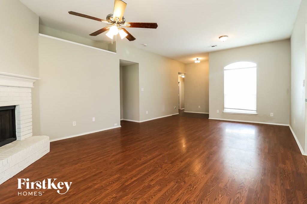 A spacious room with wooden floors and a ceiling fan.