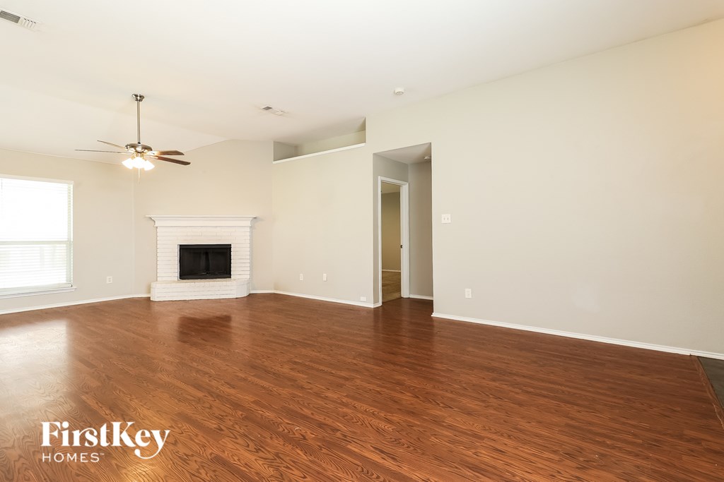 A spacious room with a fireplace and wooden flooring.