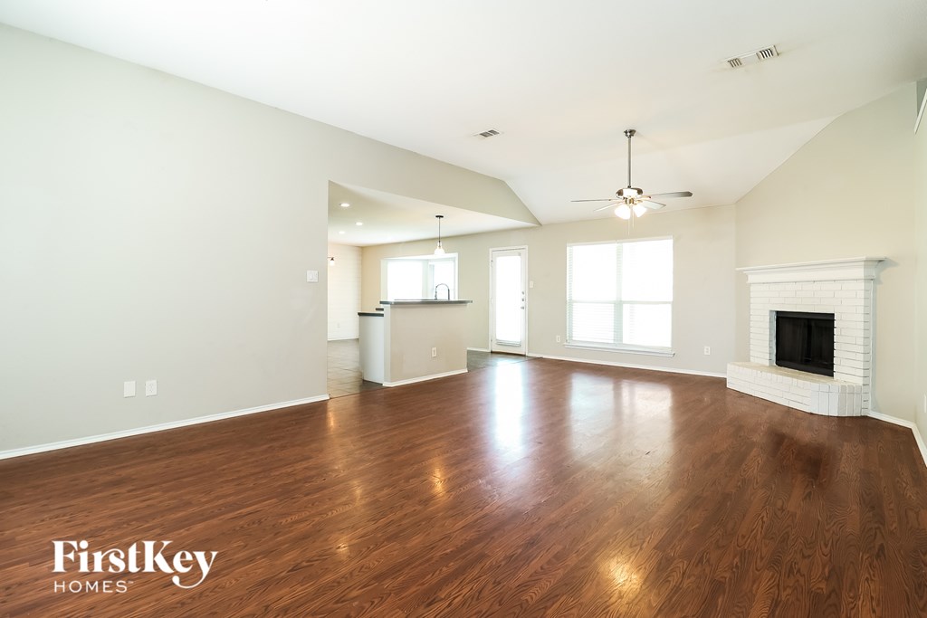 A spacious living room with wood flooring and a fireplace.