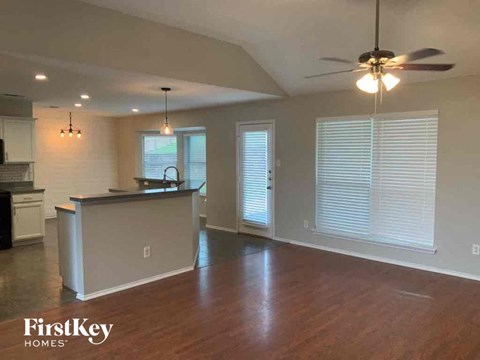 A spacious kitchen and living room with wood floors and a ceiling fan.