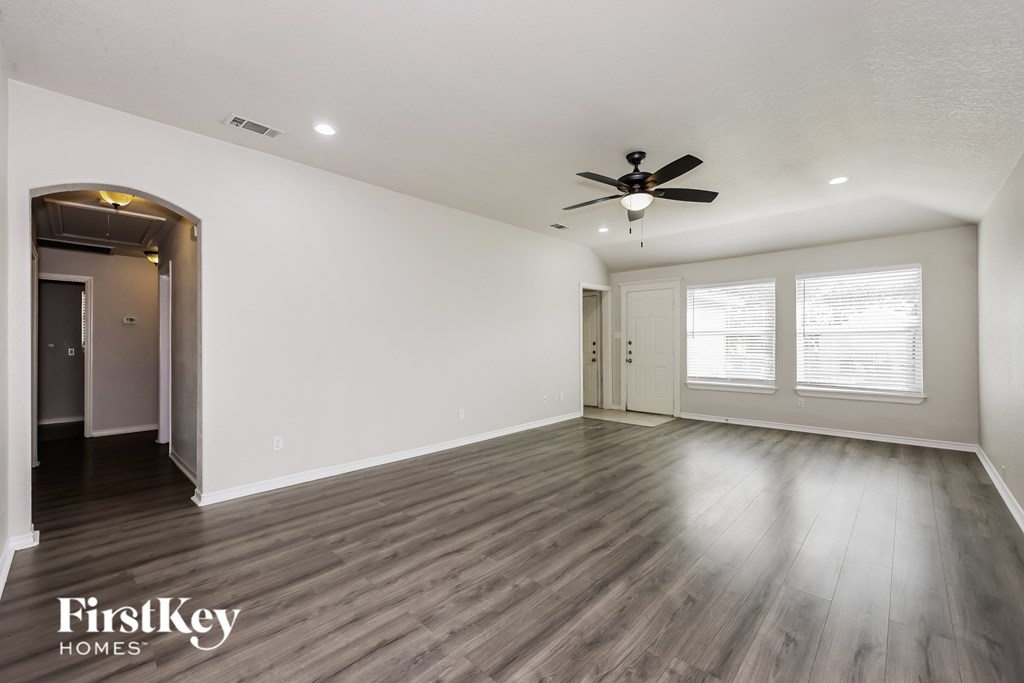 A spacious room with a ceiling fan and wooden flooring.