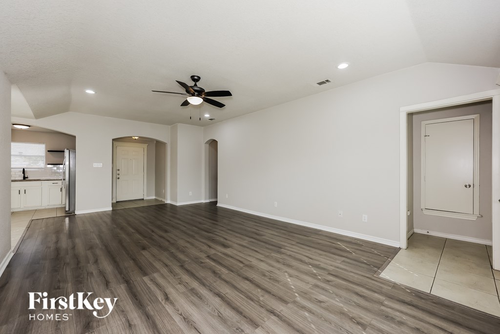 A spacious room with a ceiling fan and wooden flooring.