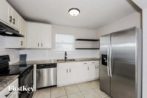 A kitchen with a stainless steel refrigerator and white cabinets.