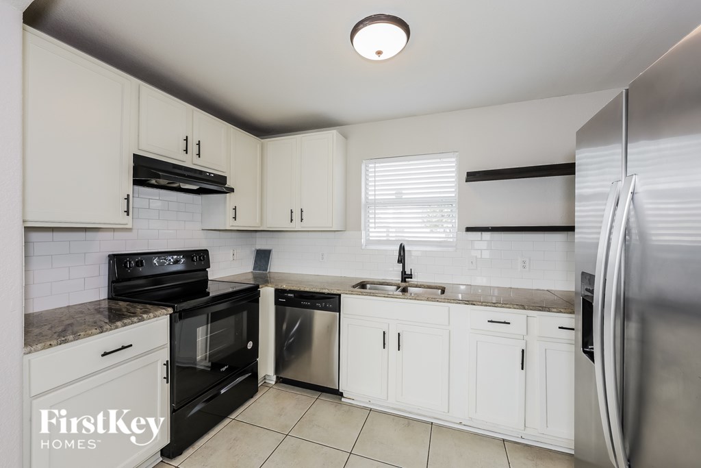 A kitchen with white cabinets and a stainless steel refrigerator.