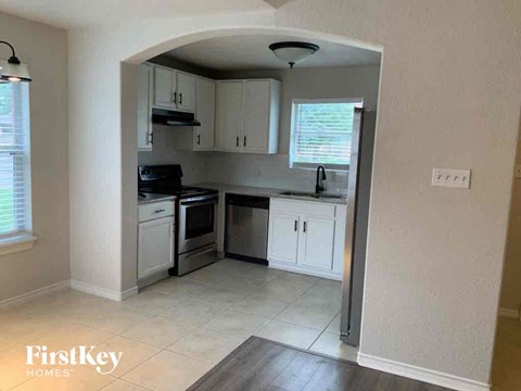 A kitchen with a white tile floor and white cabinets.