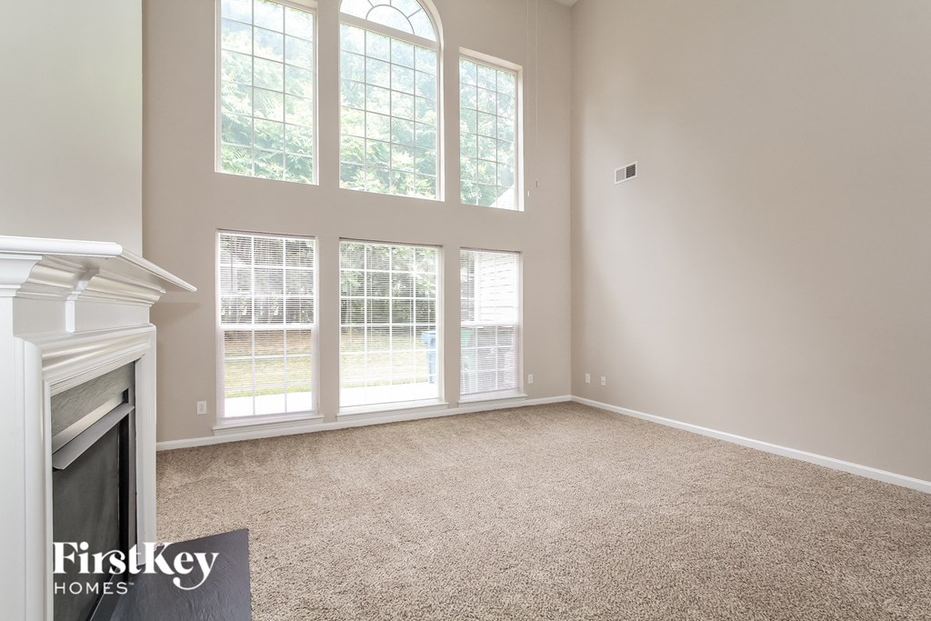 an empty living room with a fireplace and large windows