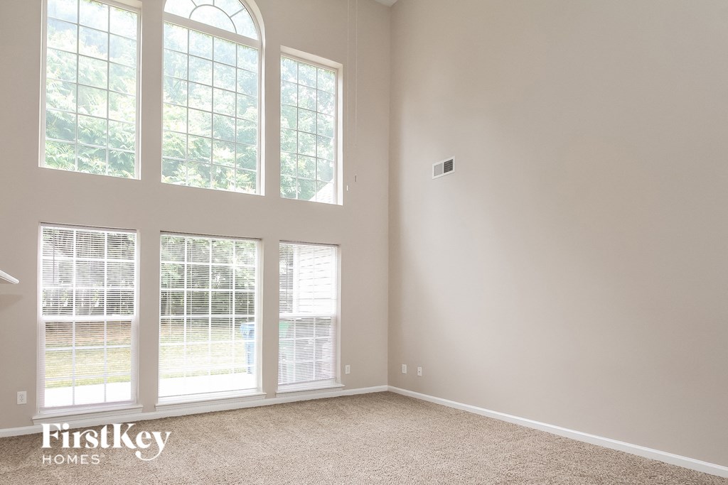 a living room with three large windows and a carpet