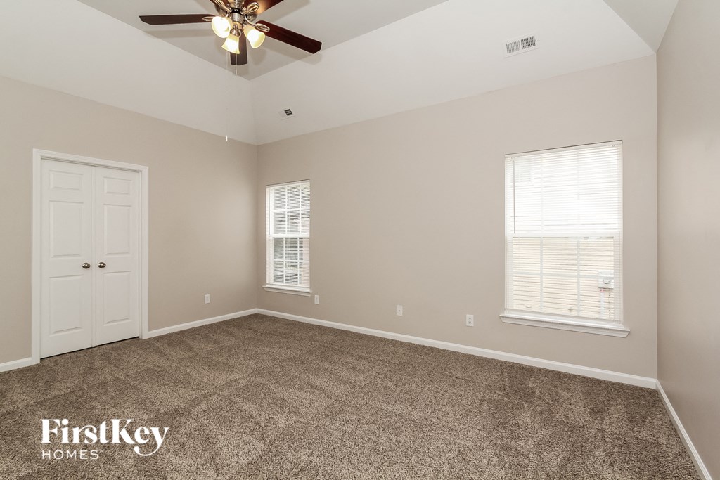 the master bedroom has a carpeted floor and a ceiling fan